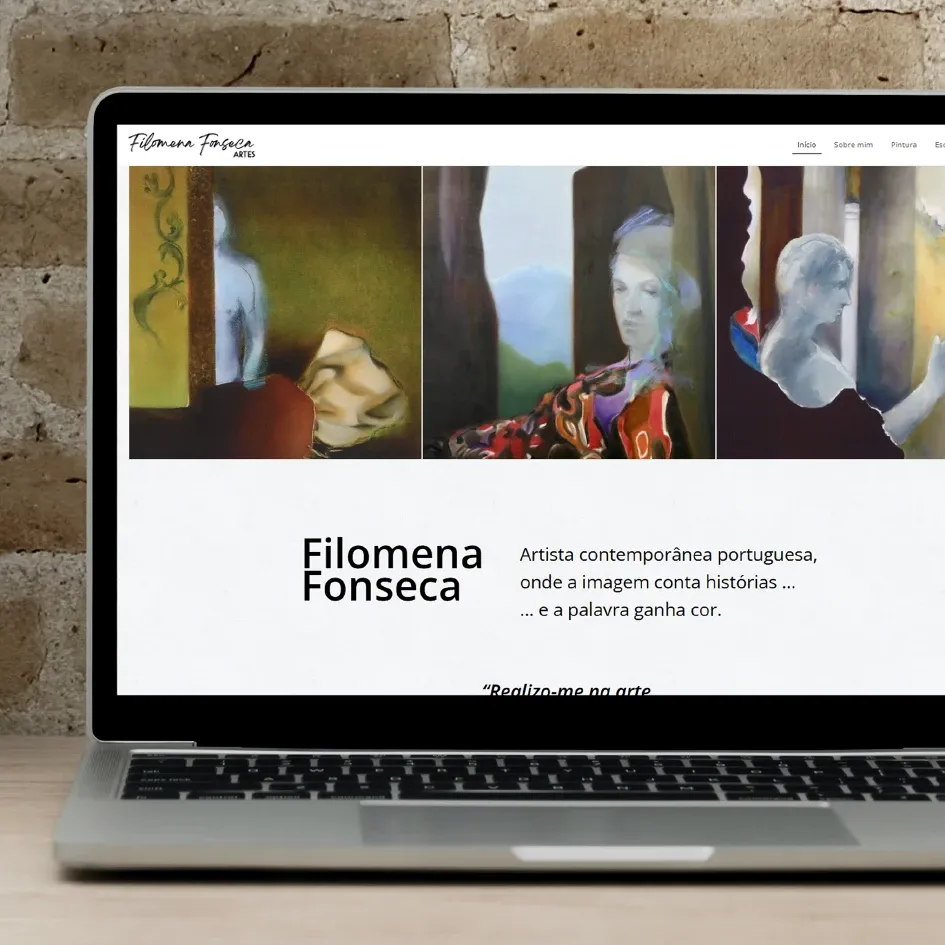 HOME Laptop com o site de Filomena Fonseca aberto, exibindo três pinturas contemporâneas em tons suaves, ao lado de pincéis num copo branco.